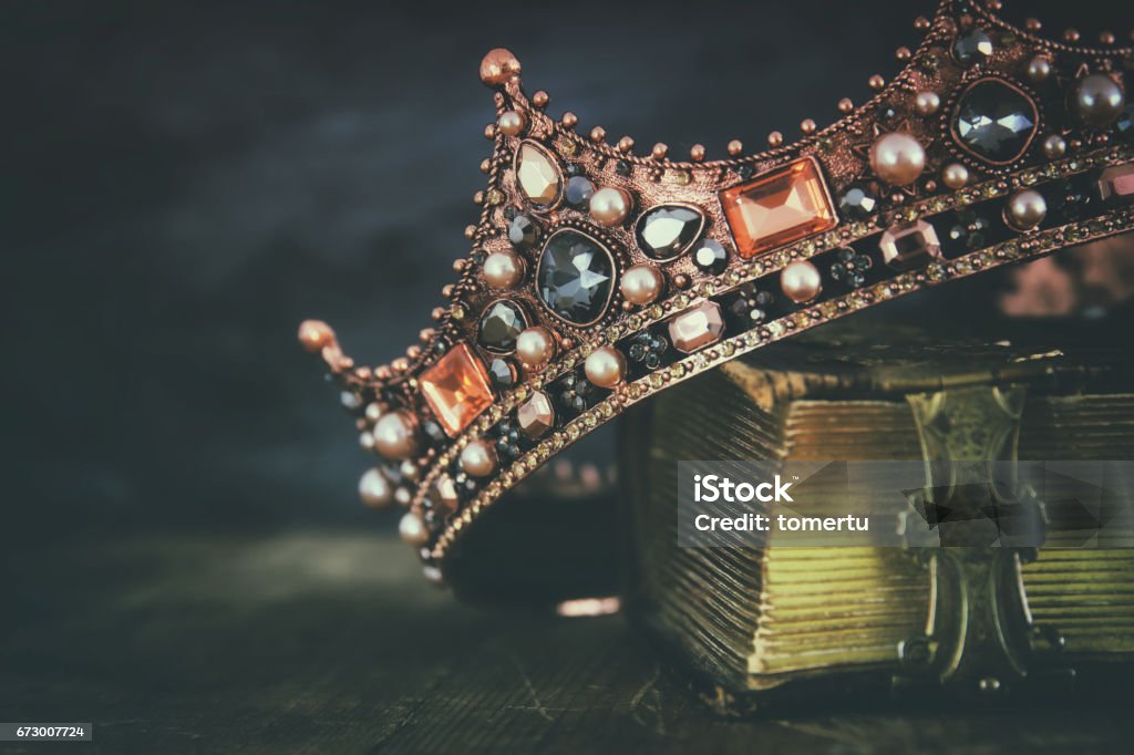 low key image of beautiful queen/king crown on old book low key image of beautiful queen/king crown on old book. vintage filtered. fantasy medieval period Crown - Headwear Stock Photo