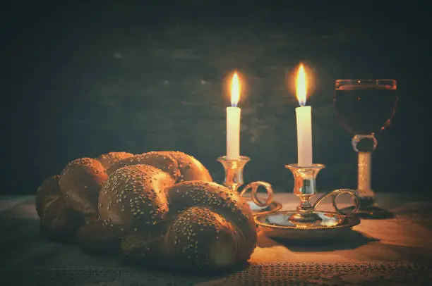 Low key shabbat image. challah bread, shabbat wine and candles on wooden table