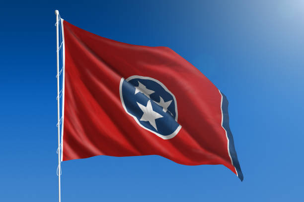 The flag of the state of Tennessee blowing in the wind in front of a clear blue sky