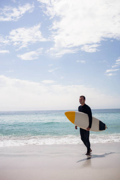 istock Happy surfer holding a surfboard on the beach 673016464