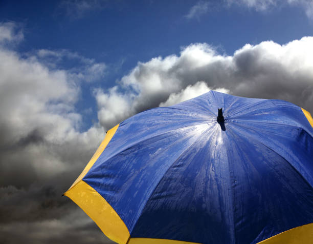 istock Blue - yellow beach umbrella on a background clouds 673027842