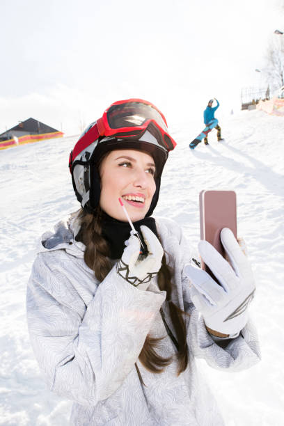 istock Female snowboarder applying lip gloss 673027886