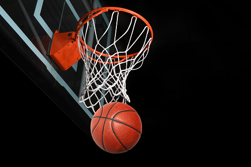 Basketball after going through hoop isolated over black background
