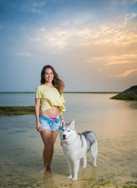 An Asian mix race woman and her Husky enjoying the beach at sunset
