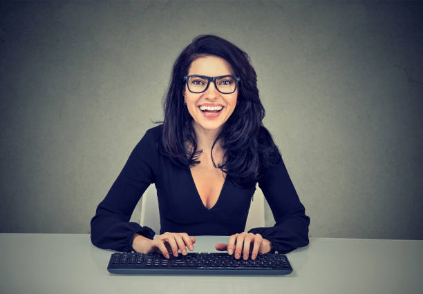 sorrindo espantado mulher digitando em um teclado de computador - making a face nerd female cheerful - fotografias e filmes do acervo