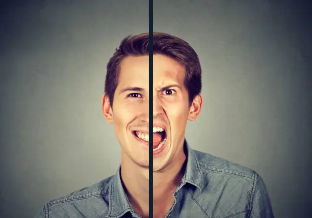 Photo of Bipolar disorder concept. Young man with double face expression isolated on gray background