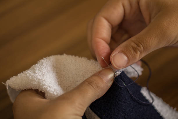 istock Woman sewing towel with needle and thread 673040452