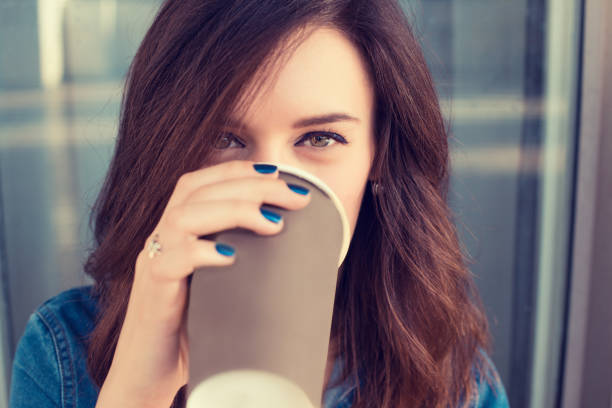 Smiling woman drinking coffee outdoors holding paper cup