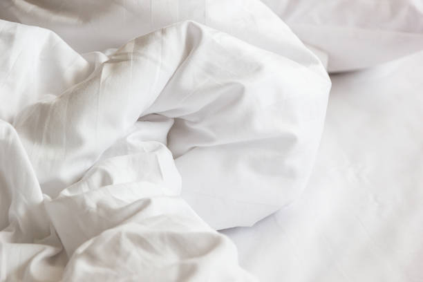 istock white pillow on bed and with wrinkle messy blanket in bedroom, from sleeping in a long night, details of duvet and blanket, an unmade bed in hotel bedroom with white blanket. 673046276