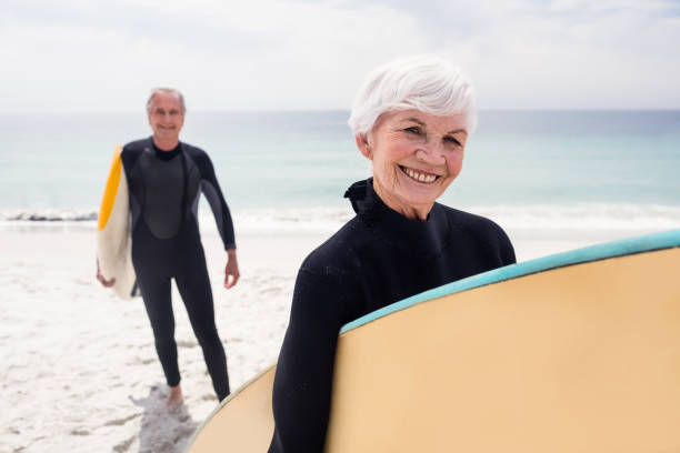istock Senior couple in wetsuit holding surfboard on beach 673051956