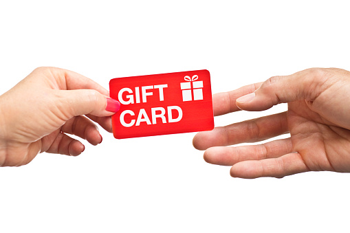 A woman's hand and a man's hand. The woman is holding a gift card handing the card to the man. Photographed on white background.