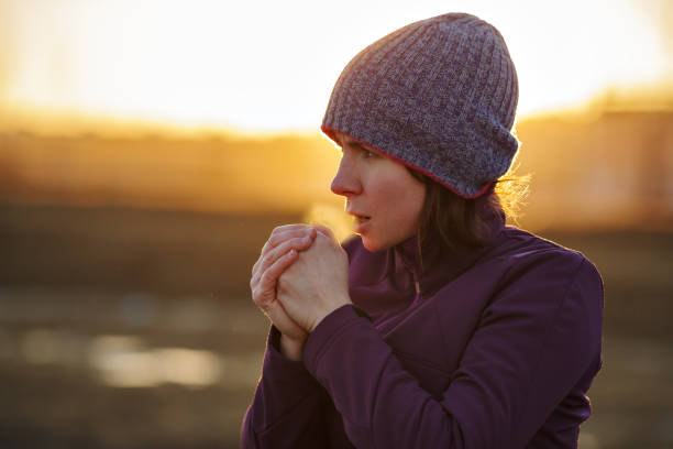 Girl going in for sport outside in cold weather A girl in sports clothes breathes in the palm of her hand trying to keep warm frost face stock pictures, royalty-free photos & images