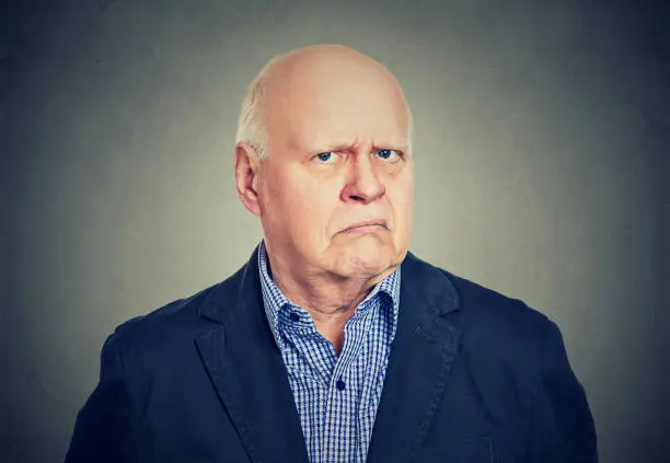 Portrait of an angry, grumpy senior business man, isolated on gray background