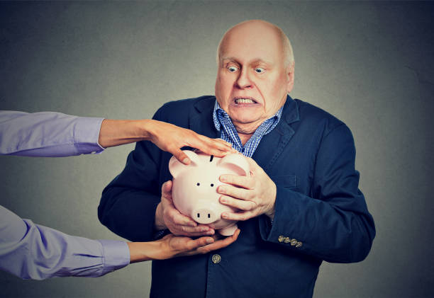 Elderly upset scared business man holding piggy bank trying to protect his savings from being stolen Elderly upset scared business man holding piggy bank trying to protect his savings from being stolen isolated gray background ponzi scheme stock pictures, royalty-free photos & images