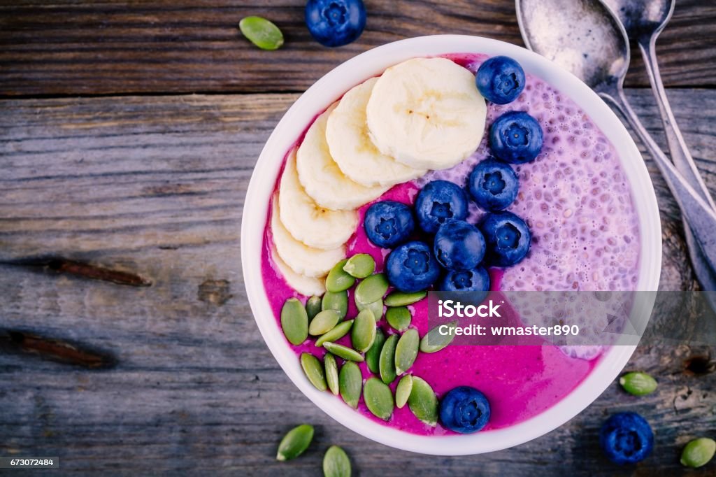 Gesundes Frühstück: lila Smoothie Schüssel mit Chia Pudding, Banane, frische Heidelbeeren und Kürbiskernen - Lizenzfrei Smoothie Stock-Foto