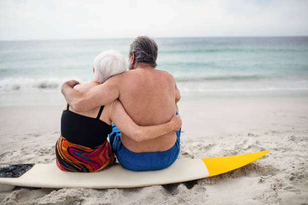istock Senior couple sitting on surfboard at beach 673079098