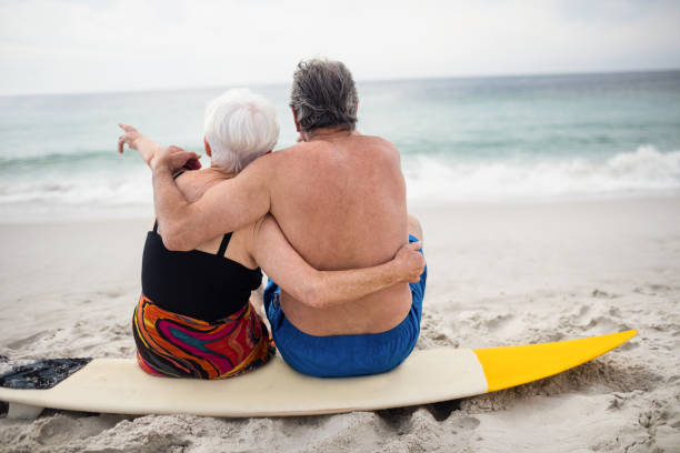 istock Senior couple sitting on surfboard at beach 673079216