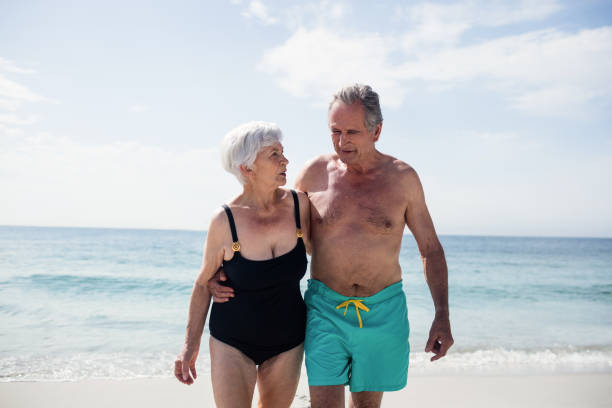 istock Happy senior couple embracing while walking on beach 673091052