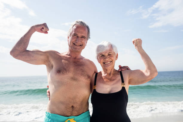 coppia senior felice che flette i muscoli - flettere i muscoli foto e immagini stock