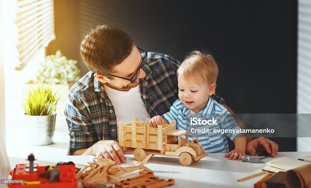 père et fils tout-petits rassemblent l’artisanat d’une voiture en bois et jouent - Photo de Père libre de droits
