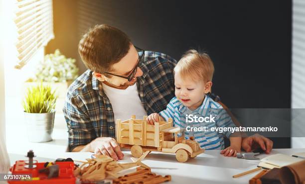 Photo libre de droit de Père Et Fils Toutpetits Rassemblent Lartisanat Dune Voiture En Bois Et Jouent banque d'images et plus d'images libres de droit de Père