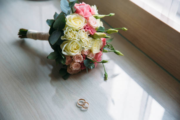 istock wedding rings and roses bouquet on background 673108044