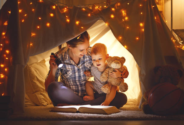 istock mother and baby son with a book and a flashlight before going to bed 673108958