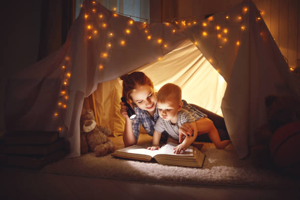 istock mother and baby son with a book and a flashlight before going to bed 673112856