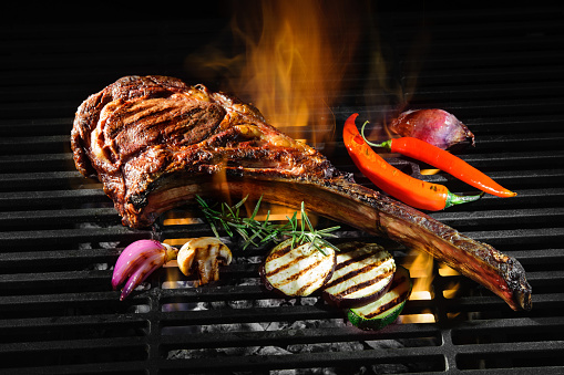 Tomahawk rib beef steak on hot black grill with flames