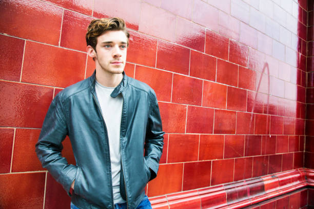 istock Millennial British man lost in thoughts while waiting against red wall 673114850