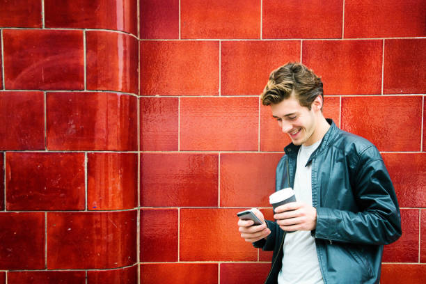 istock Millennial British man smiling as he text messages while waiting for bus 673114892