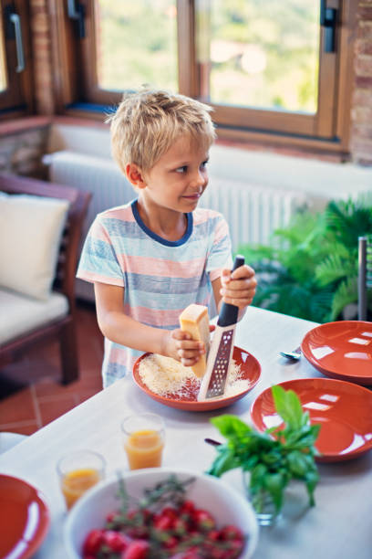 istock Little boy grating cheese for spaghetti 673123448