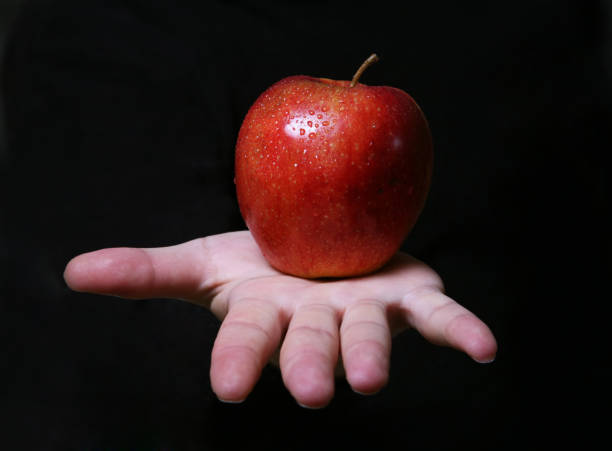 istock Man's hand with a red apple on a dark background 673123966