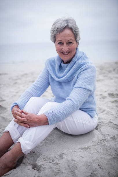 istock Happy senior woman sitting on beach 673125096