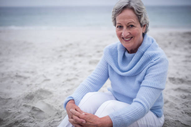 istock Happy senior woman sitting on beach 673128022