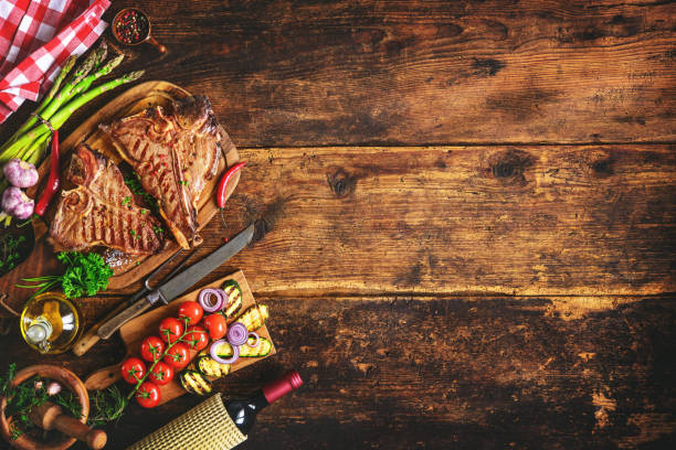 istock Grilled T-bone steaks with fresh herbs, vegetables ans wine bottle 673139318