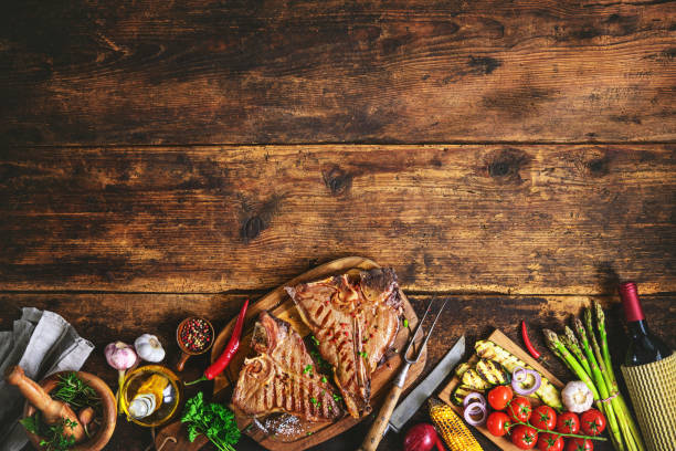 istock Grilled T-bone steaks with fresh herbs, vegetables ans wine bottle 673139326