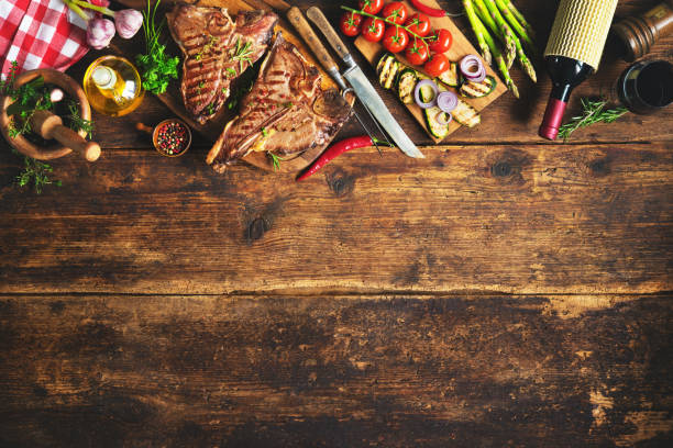 istock Grilled T-bone steaks with fresh herbs, vegetables ans wine bottle 673139330