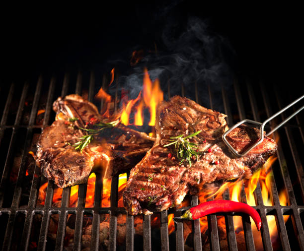 Beef T-bone steaks on the grill Beef T-bone steaks on the grill with flames t bone steak stock pictures, royalty-free photos & images