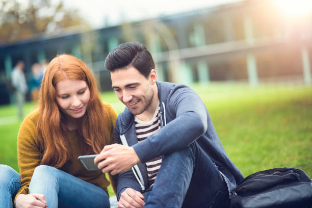 istock Young couple using smart phone in a park 673145122