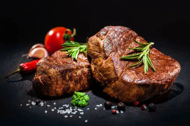 grilled beef fillet steaks with spices on dark background