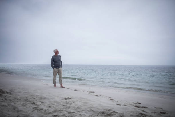 istock Thoughtful retired man standing on the beach 673155322
