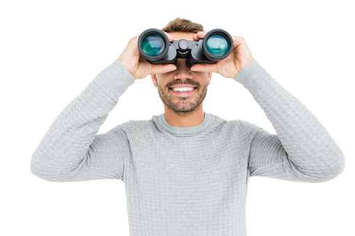 Young man looking through binocular on white background