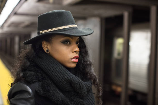 A young, black woman waits at a NYC subway platform. Shot during The Spring of 2017