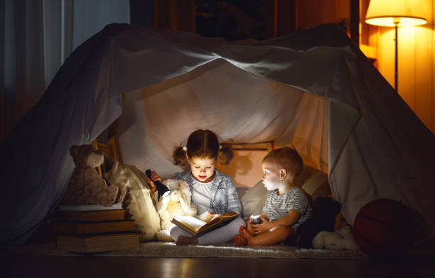 niños niño y niña leyendo libro con linterna en tienda de campaña - child bedtime imagination dark fotografías e imágenes de stock