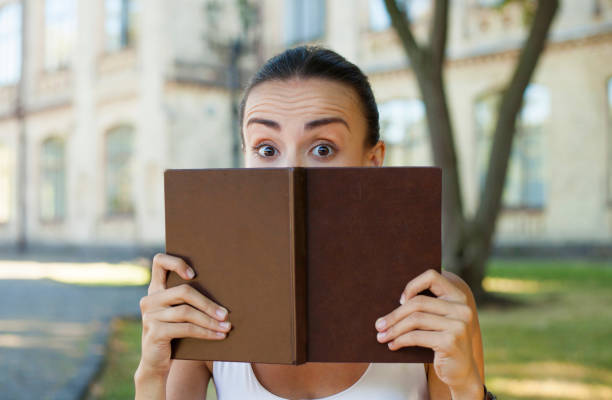 istock The girl looks out from behind a book. 673173326