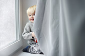 Toddler boy playing on the window sill at home