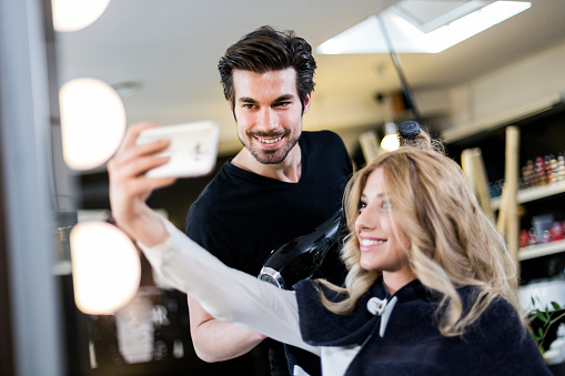 Hairdresser taking selfie with customer