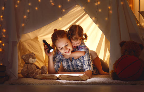 istock mother and child daughter with a book and a flashlight before going to bed 673180650