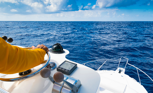 Hand of captain on steering wheel of motor boat in the blue ocean